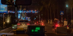 Ngh Trang beach road at night through a taxicab window.  Festive lights and so many scooters!